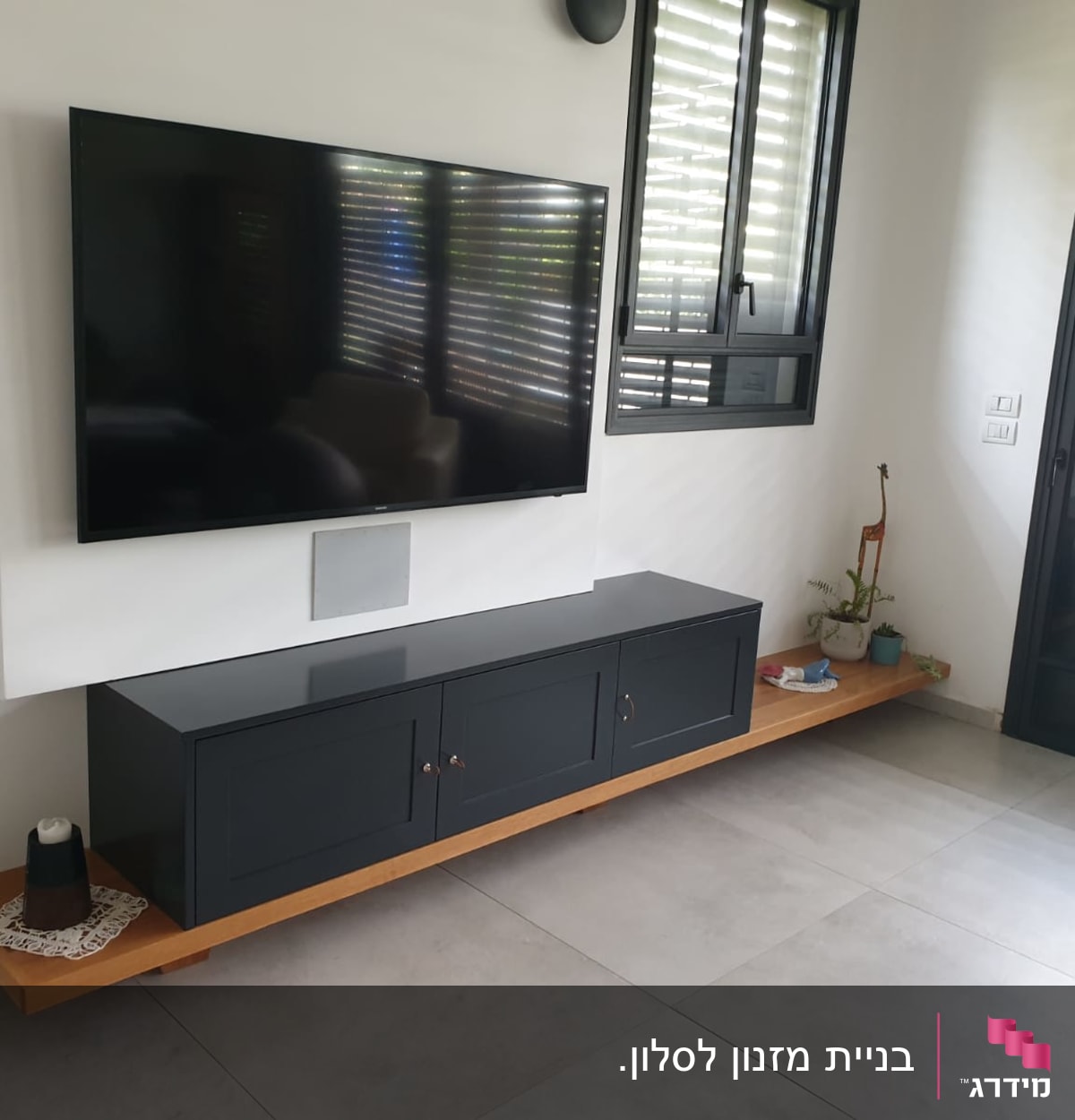 טלוויזיה תלויה על קיר עם ארונית עץ מתחת